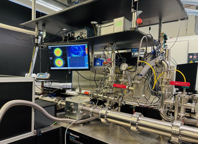 Ein komplexer Messaufbau aus silbernen Rohren, Kabeln und einem Monitor steht auf einem Tisch.