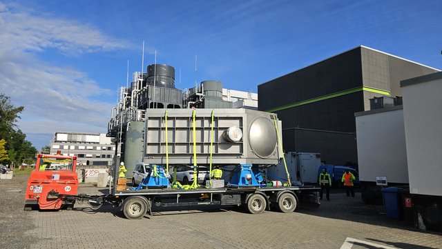A large, silver metallic chamber is positioned on a trailer.