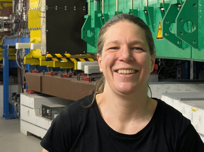 Eine Frau steht vor einem großen, grünen Magneten.